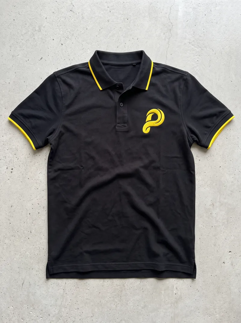 Camiseta polo negra con la P de Pista bordada en amarillo